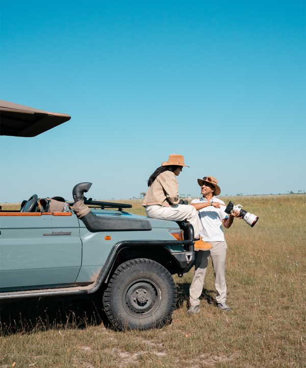 Luxury safari experiences- a couple next to a safari jeep